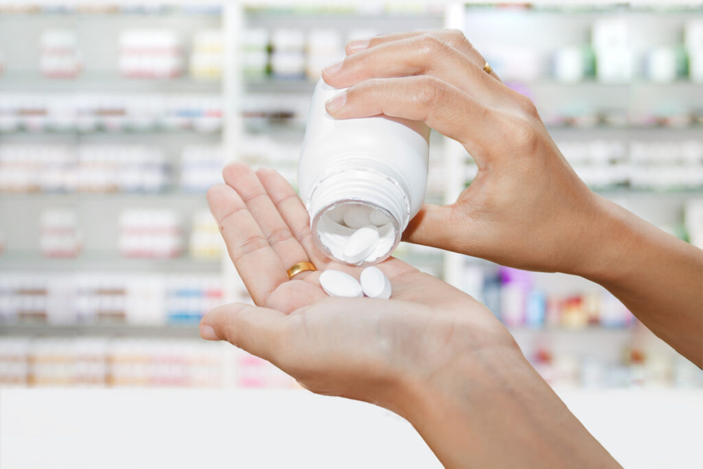 hand of doctor holding medicine bottle on medicine cabinet and s